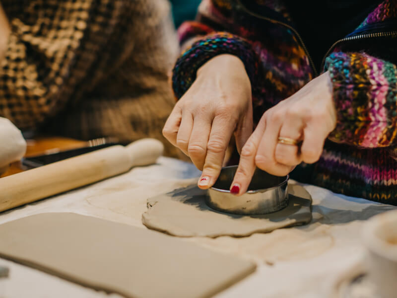 Hands pushing a mould into a piece of clay